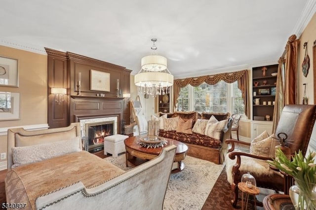 living area with ornamental molding, a chandelier, and a high end fireplace