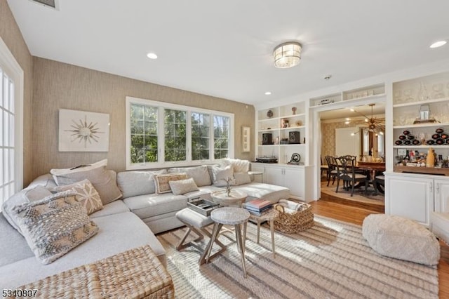 living room with built in shelves, recessed lighting, light wood-style flooring, and wallpapered walls