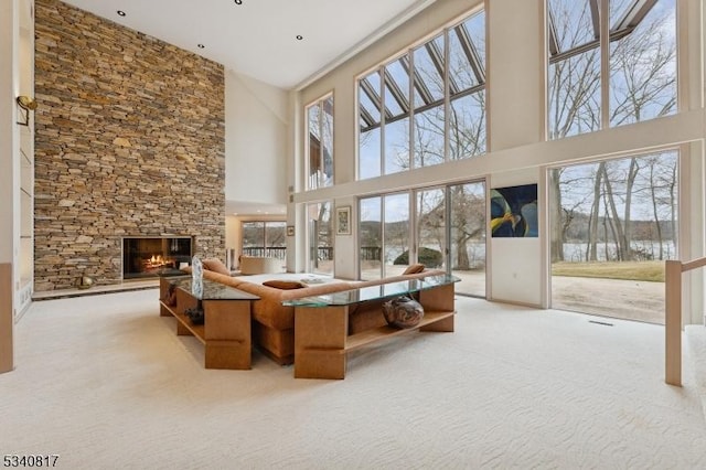 living area with light carpet and a stone fireplace