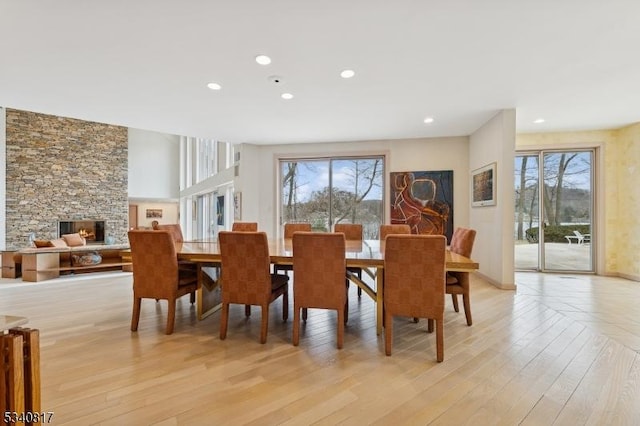 dining area featuring light wood-style flooring, a fireplace, baseboards, and recessed lighting