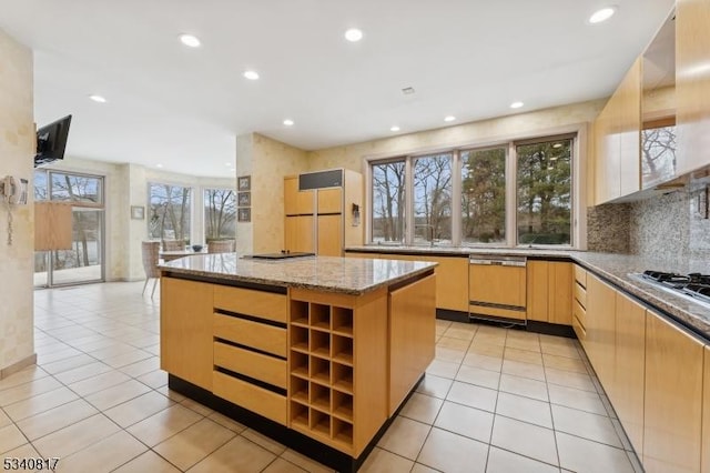 kitchen with paneled dishwasher, a kitchen island, light stone counters, light brown cabinets, and built in fridge