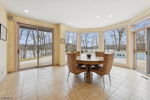 dining space featuring recessed lighting, a water view, and light tile patterned floors