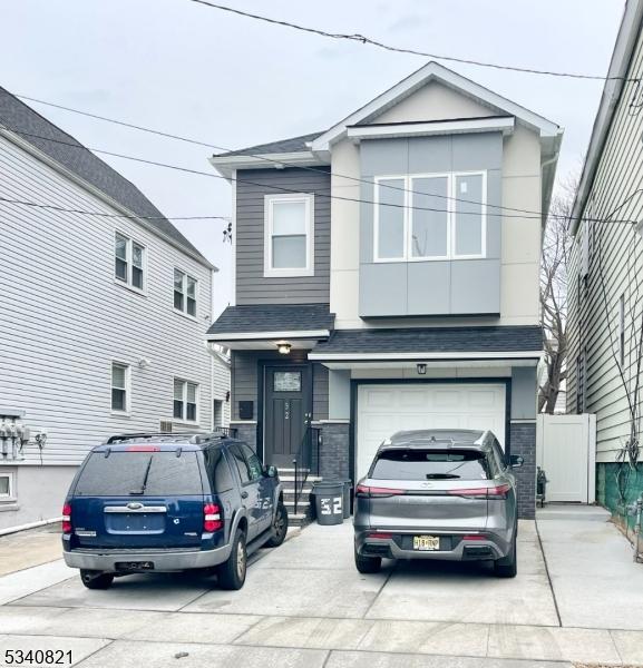 view of front of home featuring driveway, roof with shingles, an attached garage, and fence