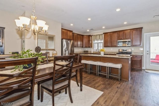 kitchen with a chandelier, dark wood-style flooring, a sink, appliances with stainless steel finishes, and a center island