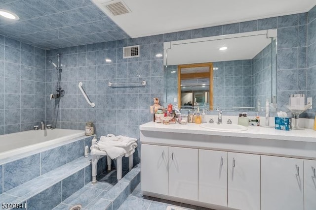 bathroom featuring visible vents, tiled shower / bath combo, tile walls, and vanity