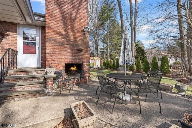 view of patio featuring an outdoor brick fireplace and outdoor dining space