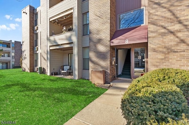 doorway to property featuring a balcony, a lawn, and brick siding