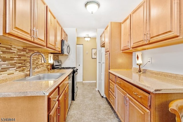 kitchen with light tile patterned flooring, stainless steel appliances, a sink, light countertops, and decorative backsplash