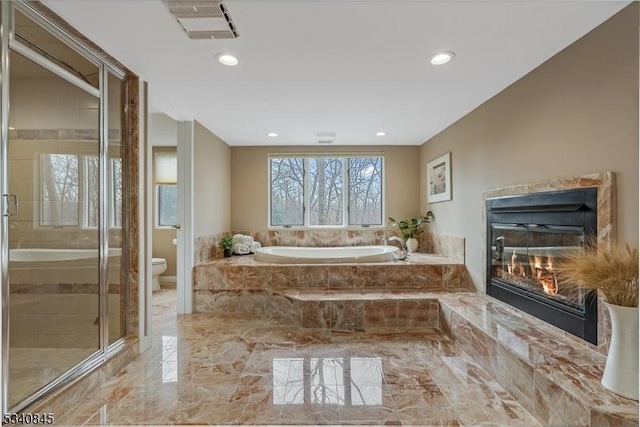 bathroom with visible vents, toilet, marble finish floor, a glass covered fireplace, and a bath