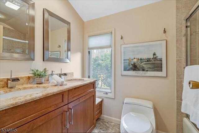 full bathroom with double vanity, toilet, a tile shower, and a sink