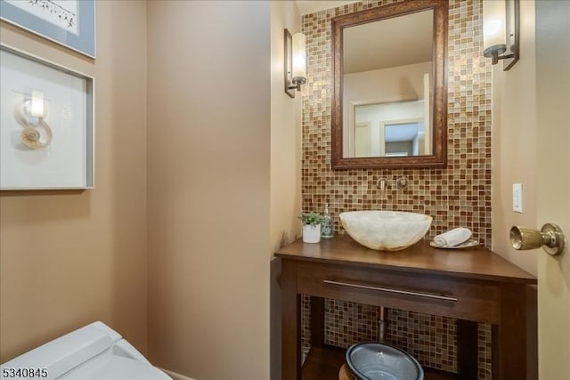 bathroom featuring vanity, toilet, and backsplash