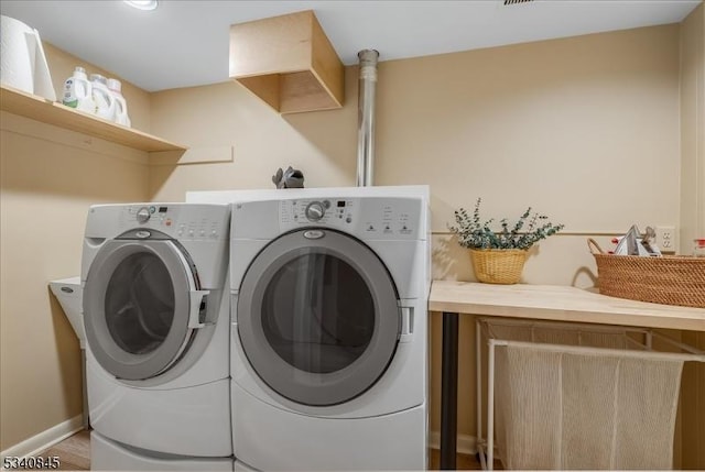 clothes washing area featuring laundry area, washer and dryer, and baseboards