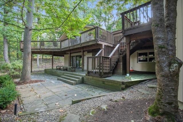 rear view of property with stairway, a deck, stucco siding, and a patio area