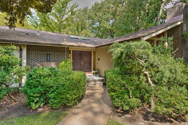 doorway to property with brick siding and a chimney