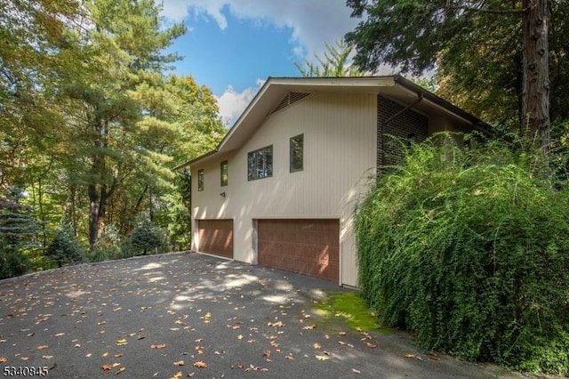 view of side of home featuring aphalt driveway and a garage