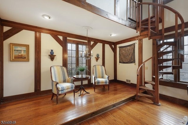 sitting room with visible vents, baseboards, hardwood / wood-style flooring, an inviting chandelier, and stairs