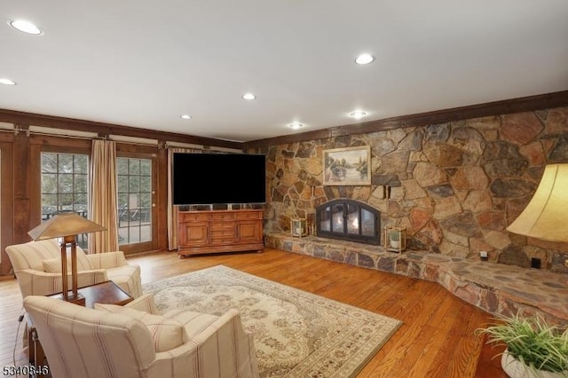 living area featuring light wood finished floors, recessed lighting, and a stone fireplace