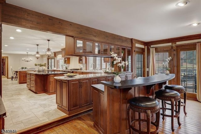 bar with stainless steel gas cooktop, recessed lighting, light wood-type flooring, and an inviting chandelier