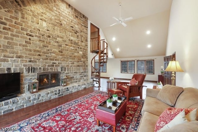 living area featuring stairs, a fireplace, high vaulted ceiling, and wood finished floors