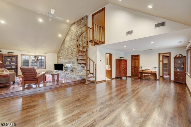 living room featuring high vaulted ceiling, stairway, visible vents, and wood finished floors