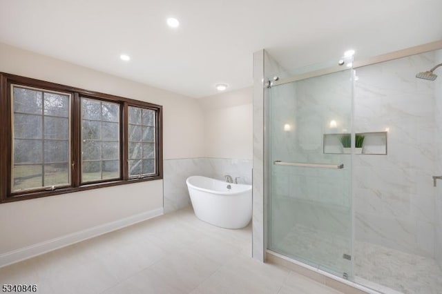 full bath with a freestanding tub, a marble finish shower, tile walls, and recessed lighting