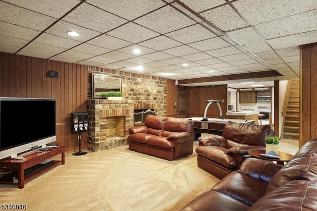 carpeted living area featuring a fireplace, recessed lighting, visible vents, stairway, and wooden walls