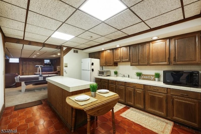 kitchen with black microwave, a toaster, visible vents, backsplash, and freestanding refrigerator