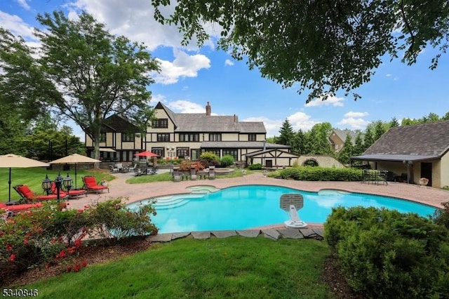 view of swimming pool with a pool with connected hot tub, a patio, and a lawn