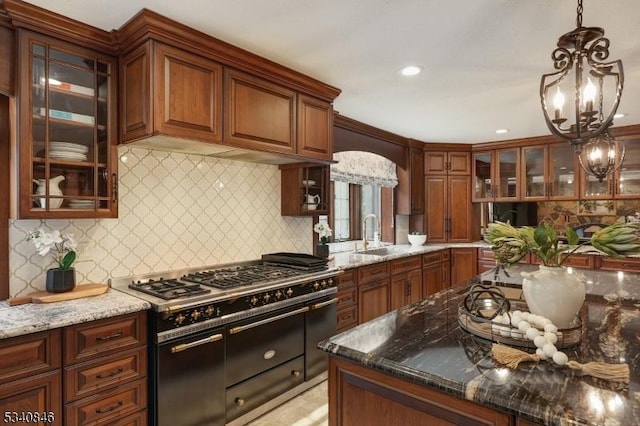 kitchen featuring dark stone counters, range with two ovens, a sink, and pendant lighting