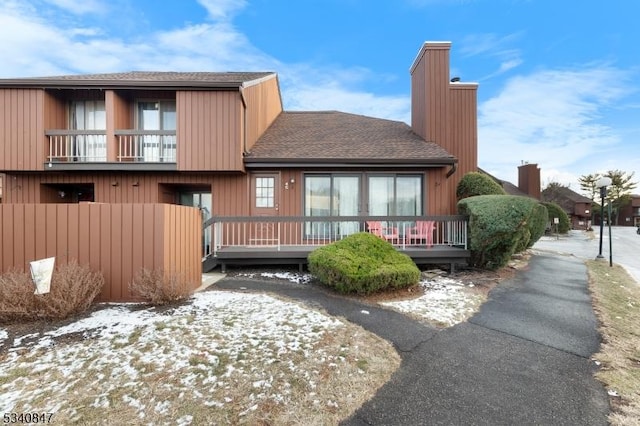 back of house featuring a shingled roof and a balcony