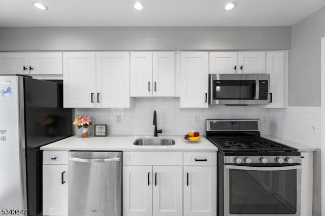 kitchen featuring stainless steel appliances, a sink, light countertops, and white cabinets