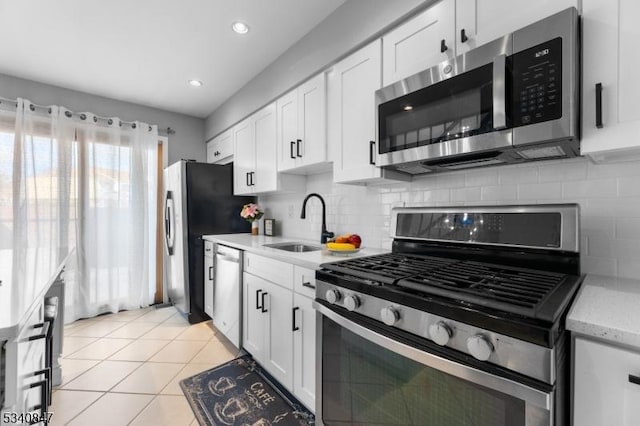 kitchen with light tile patterned floors, stainless steel appliances, a sink, and white cabinetry