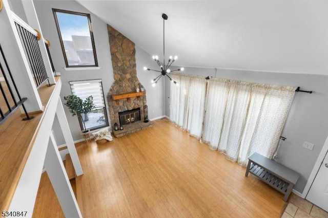 living room with a healthy amount of sunlight, a fireplace, wood finished floors, and an inviting chandelier