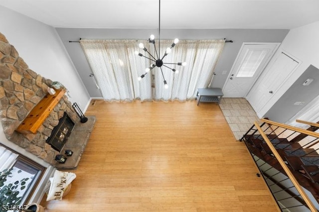 interior space featuring stairway, a fireplace, wood finished floors, and a notable chandelier