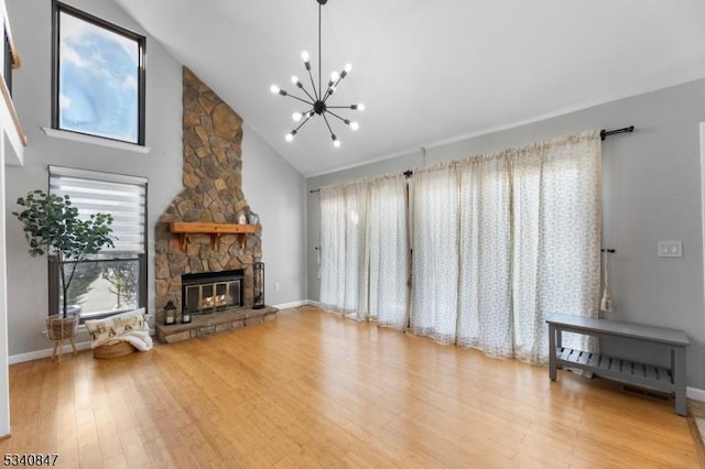 unfurnished living room with baseboards, wood finished floors, an inviting chandelier, a fireplace, and high vaulted ceiling