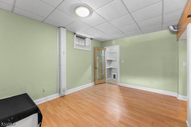 interior space featuring a paneled ceiling, baseboards, and wood finished floors