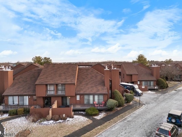 exterior space with a residential view, roof with shingles, and fence