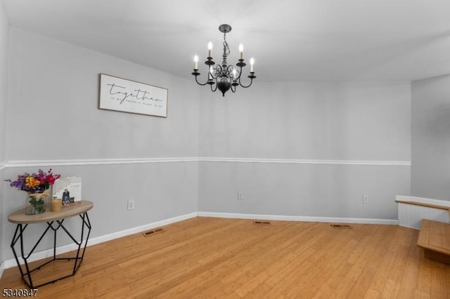 spare room with light wood-type flooring, visible vents, and baseboards