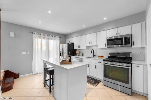 kitchen featuring stainless steel appliances, tasteful backsplash, light countertops, white cabinets, and a sink