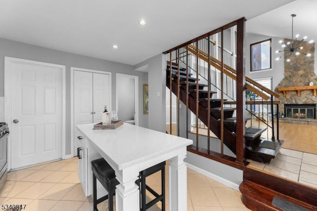 kitchen with light tile patterned floors, baseboards, a center island, a stone fireplace, and recessed lighting