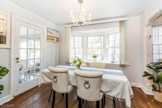 dining space featuring baseboards, a notable chandelier, arched walkways, and wood finished floors