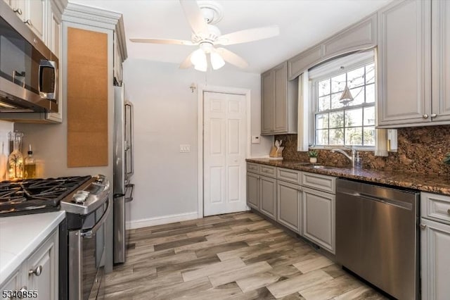 kitchen with decorative backsplash, appliances with stainless steel finishes, light wood-style floors, ceiling fan, and baseboards