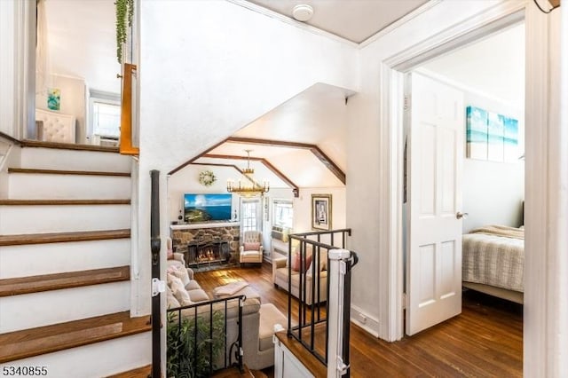 staircase featuring a stone fireplace, wood finished floors, and crown molding