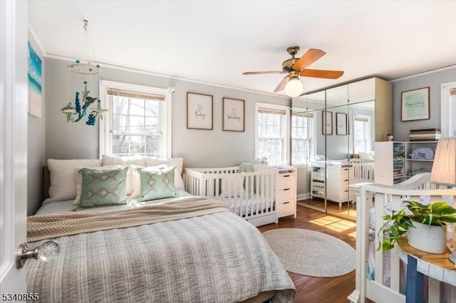 bedroom featuring ornamental molding, wood finished floors, and a ceiling fan