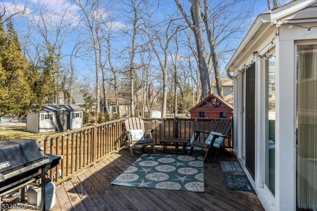 wooden terrace featuring a shed, grilling area, and an outdoor structure