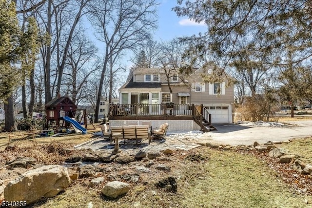 view of front of property with playground community, a deck, and an attached garage