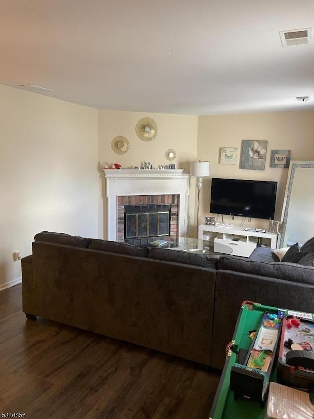 living area with dark wood-style flooring, visible vents, and a fireplace