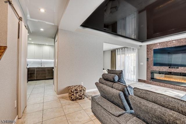 living room featuring a glass covered fireplace, recessed lighting, baseboards, and light tile patterned floors