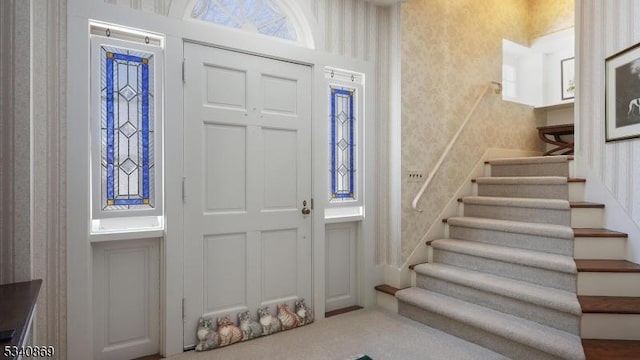 foyer entrance featuring stairway and wallpapered walls