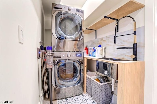 clothes washing area with laundry area, stacked washer and clothes dryer, and a sink